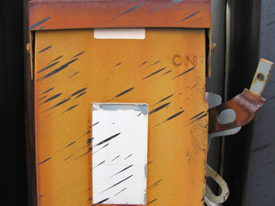 Artfully splashed tar across the face of a rusty electrical box.