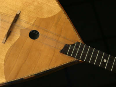 Balalaika:  a stringed instrument of Russian origin, with a characteristic triangular body and 3 sets of strings.