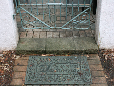 Mixed messages:  a welcome mat and a locked gate.