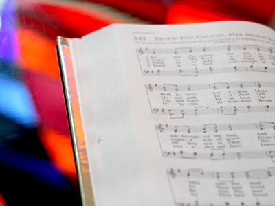 Hymnal on piano near stained glass window.