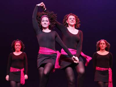 Girls in black dresses with red satin sashes.