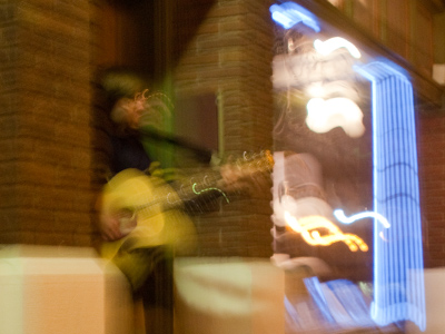 A cold guitarist performing in a doorway in the Oregon District.  If I had STOPPED WALKING to take this picture, then I would`ve had to put some money in his guitar case.