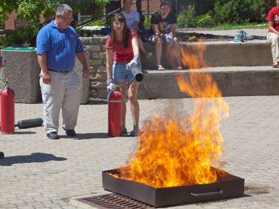 A raging fire erupts in the middle of campus, conveniently located inside a metal bin.