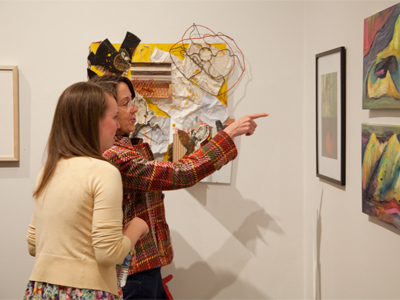 Art instructor talks to senior photography major about her own photos.