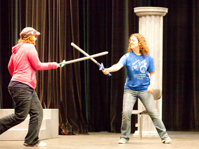 Stagehands play around with rubber swords.