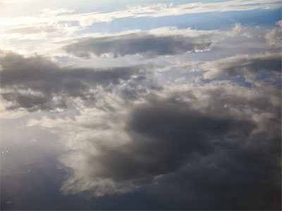 Cloudy sky upside down in a smooth river.