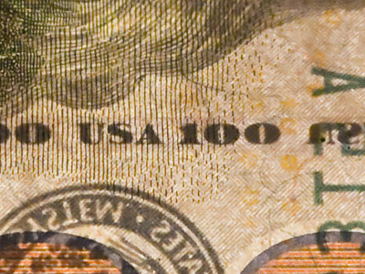 A security thread that says USA 100 is embedded in the bill, and it glows pink when exposed to ultraviolet light.