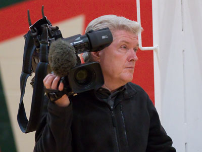 The glamorous life of a TV sportscaster:  operating the camera himself at a junior college basketball game.