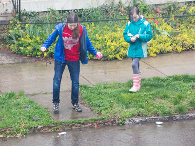 A couple of free-range children racing handmade boats in the rain.