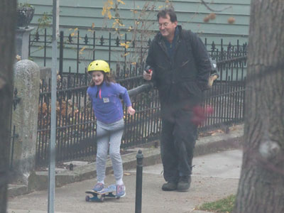 Dad uses leaf blower to propel skateboarding daughter along the sidewalk.  Dayton is the home of invention.