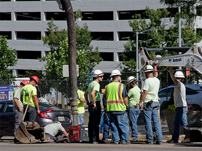 Two guys do the work, eight guys stand around and talk.