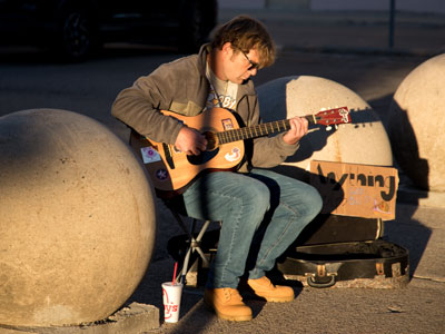 Making a living with a six-string and a cardboard sign.